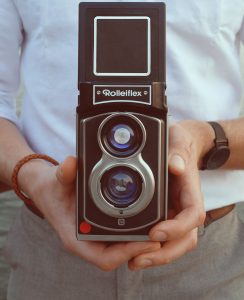 Fotograf hält Rolleiflex-Sofortbildkamera in den Händen