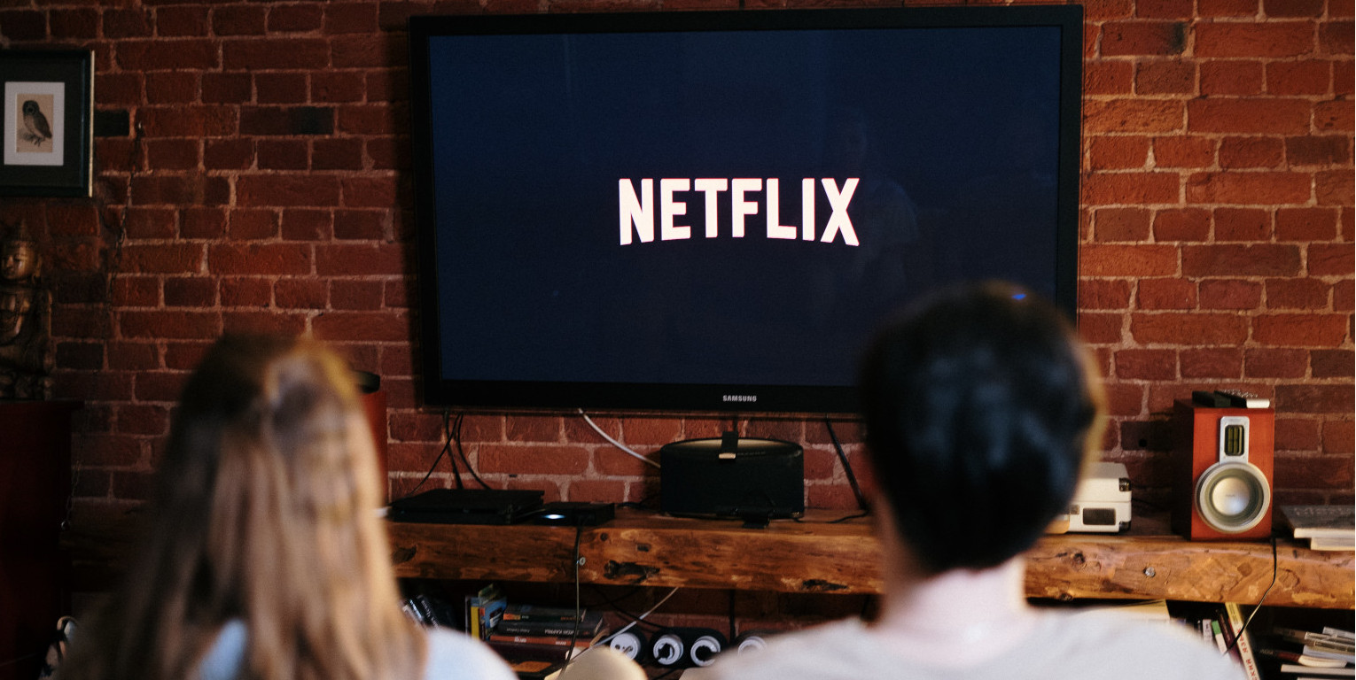 Junge und Mädchen sitzen vor flachem Fernseher mit Netflix-Logo