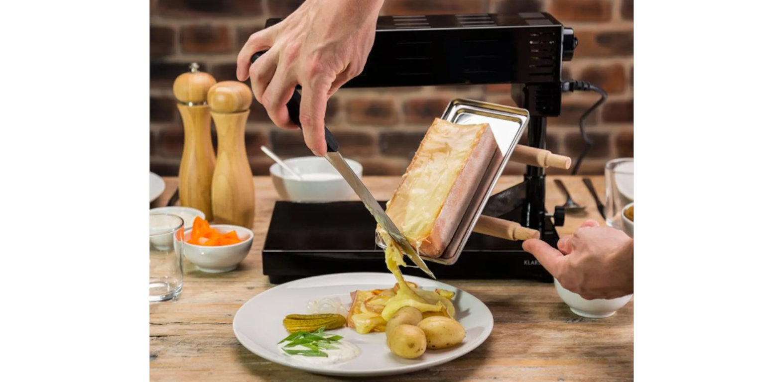 Hand schiebt Käse von Schweizer Raclette auf Teller